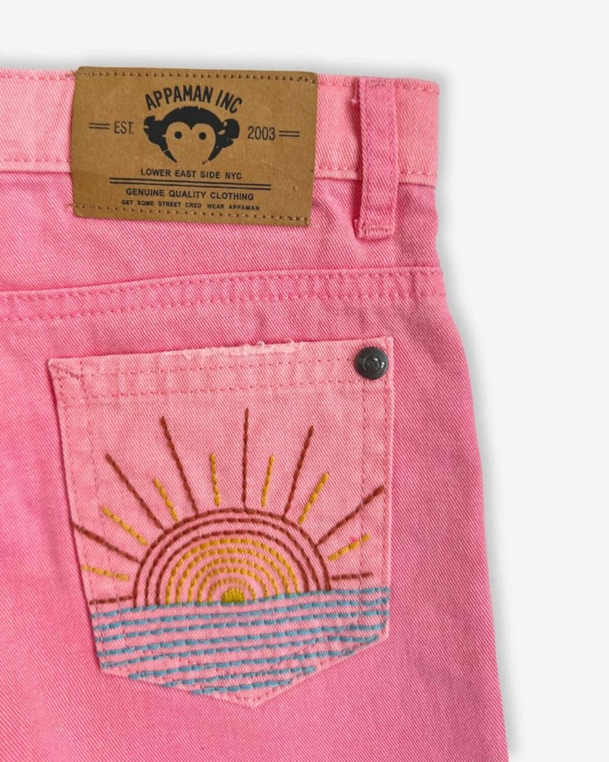 Cheerful stitched sunrise on the back pocket of Appaman's pink denim shorts, perfect for stylish kids exploring the world.