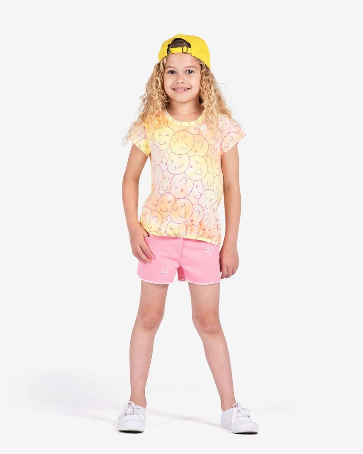 Bright-eyed kid rocking a smiley tee and pink shorts, the ultimate stylish combo for back-to-school fun in kids clothes!