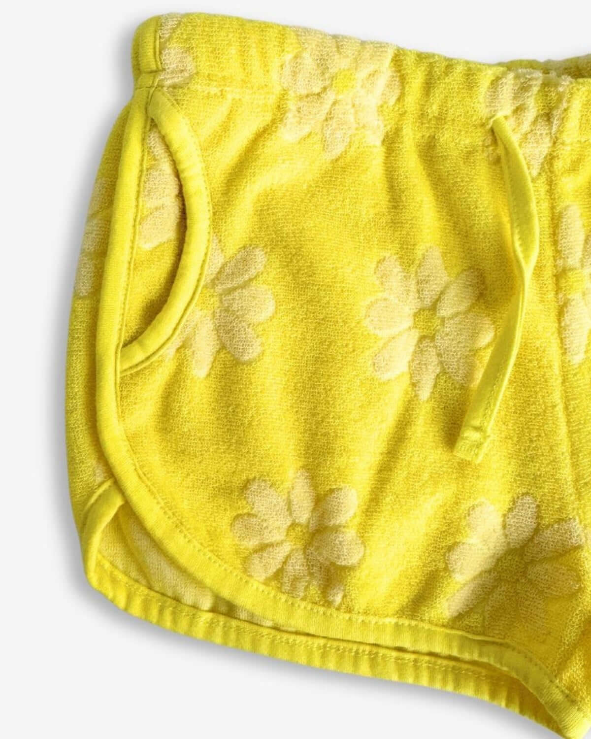 Cheerful summer daisy print terry shorts for kids, featuring comfy pockets and playful adjustable drawstring.