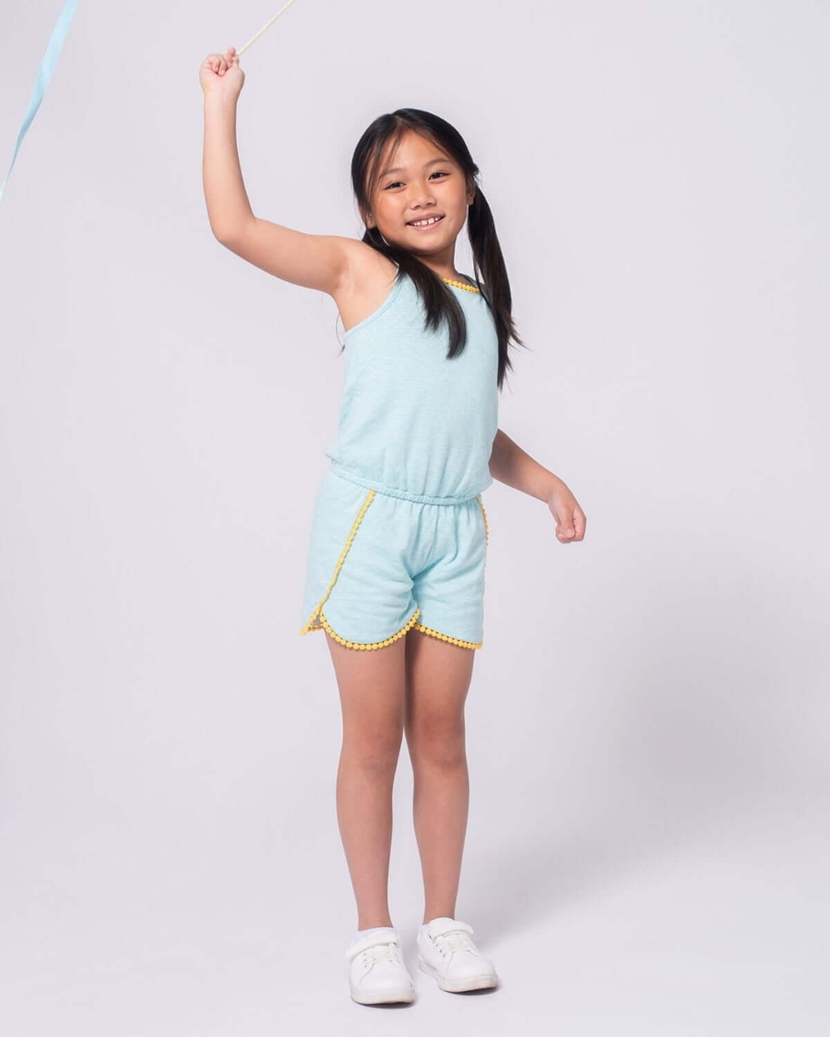 Aqua Novia Romper worn by a girl playing happily, featuring playful yellow outline detailing.