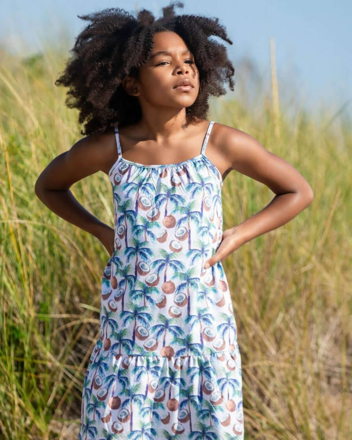 Coconut Palms Scarlett Dress showcased on a young girl in a sandy, grassy area, perfect for summer adventures.