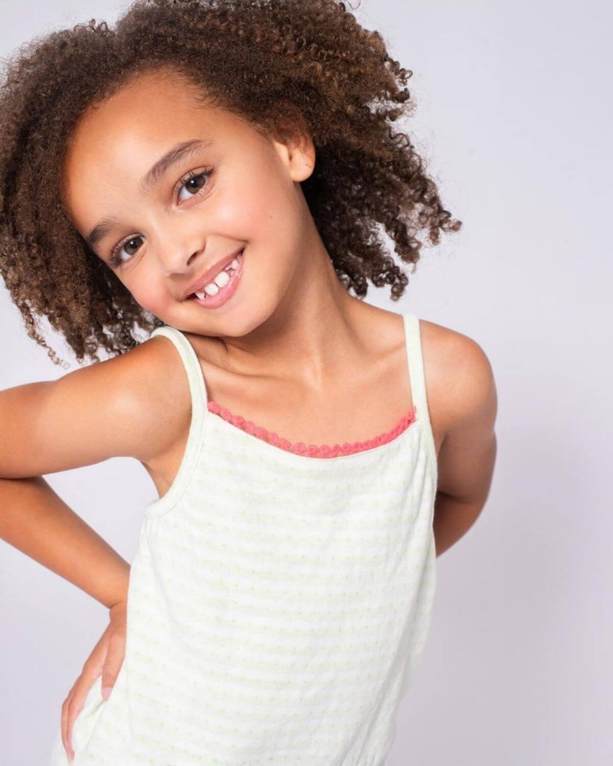 Light Green Stripe Novia Romper modeled by a smiling girl with curly hair, showcasing a playful and chic design.