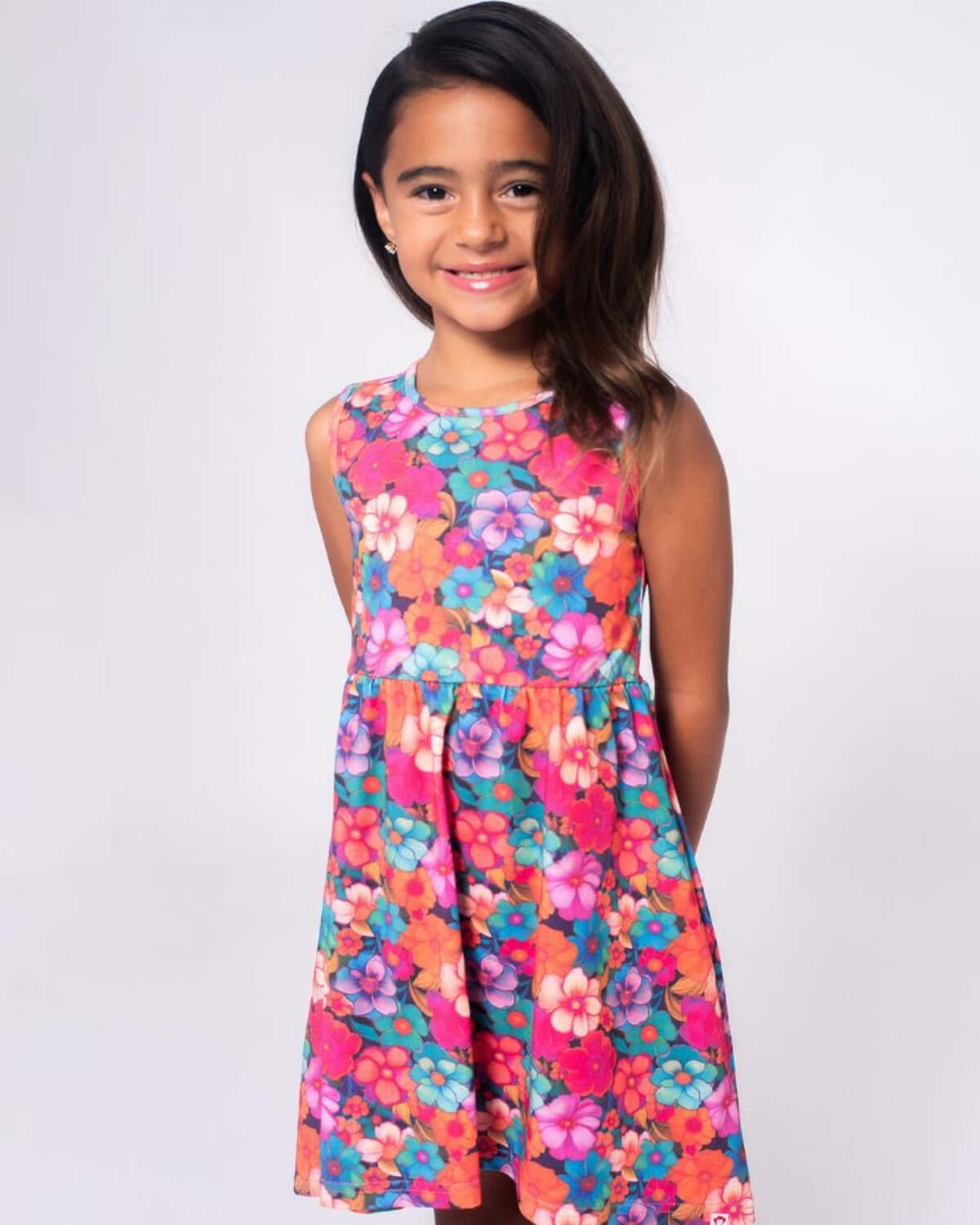 Girl wearing the Summer Bloom Naxios Dress featuring a colorful floral design, perfect for sunny days.