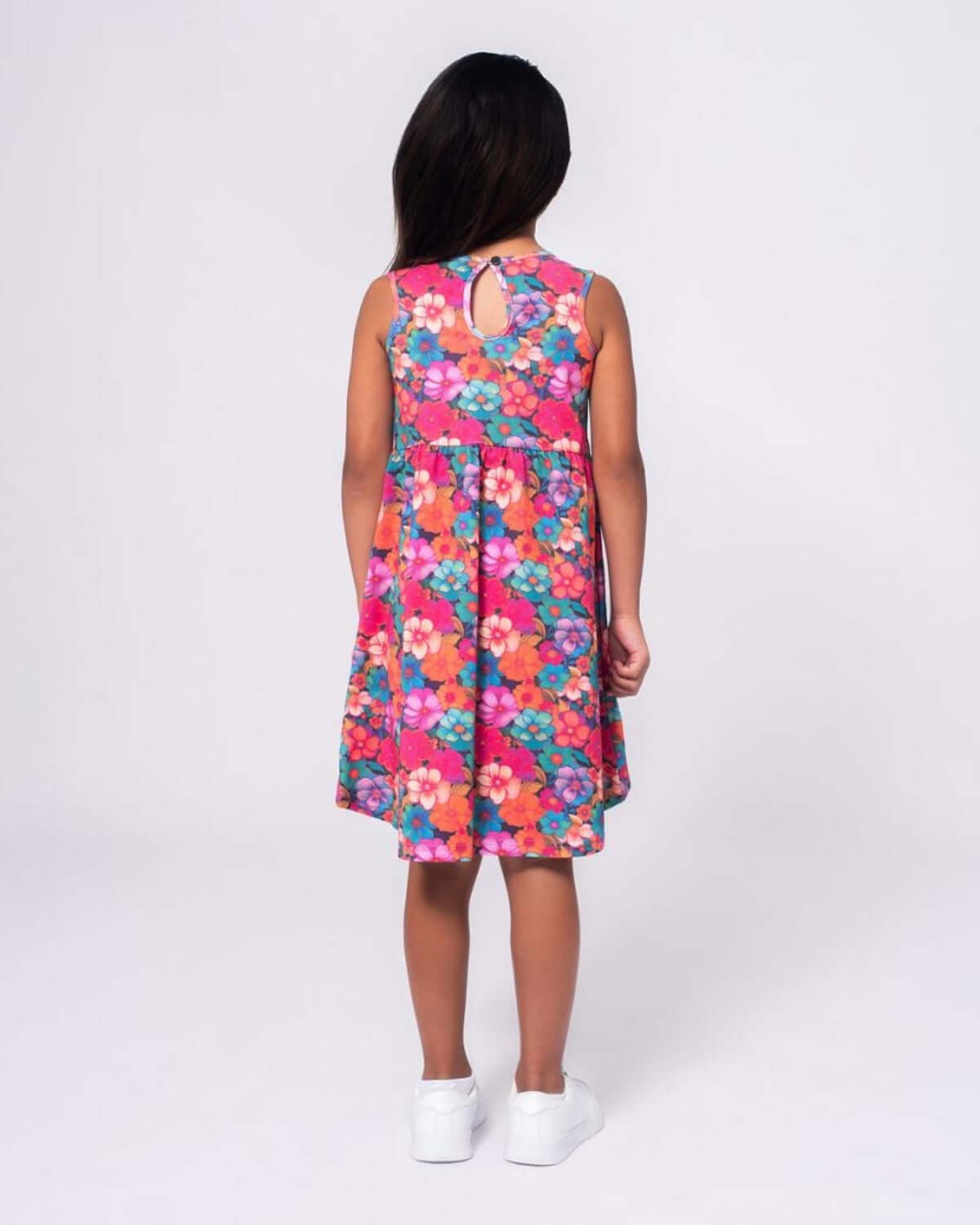 Back view of a girl wearing the Summer Bloom Naxios Dress with a colorful floral pattern.