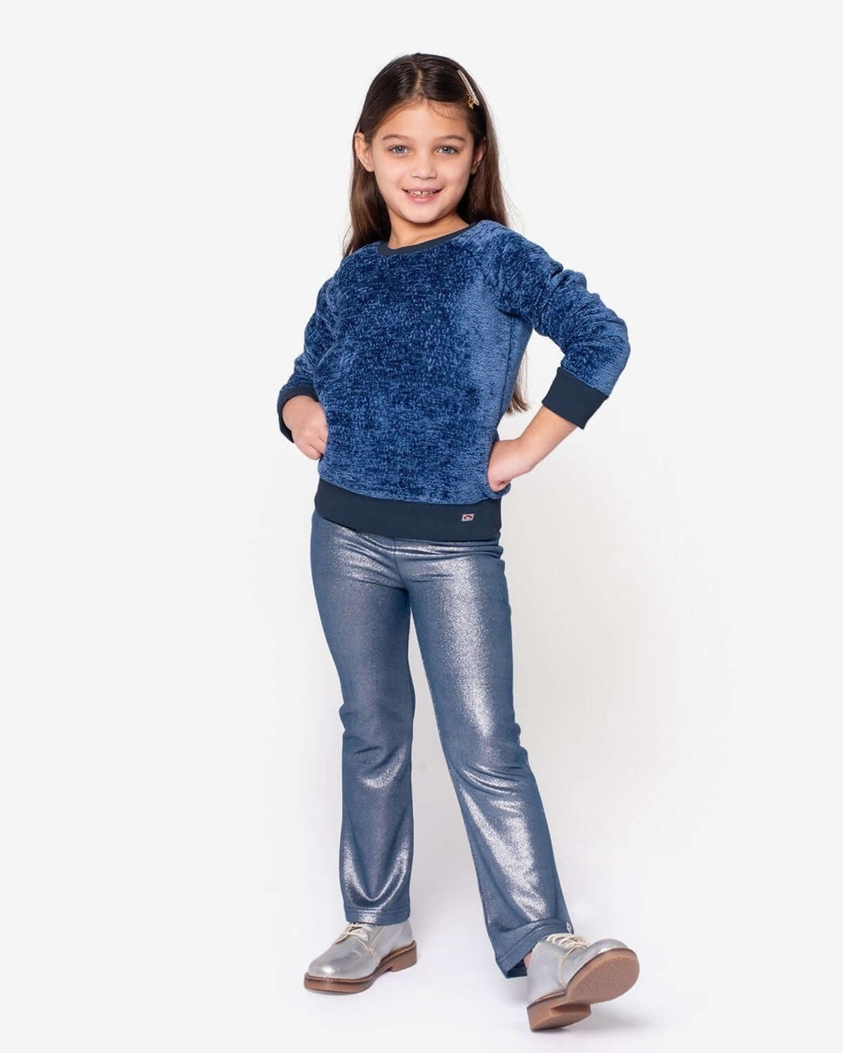 Stylish girl in a navy velvet Willow Top and shiny silver pants, showcasing playful winter fashion for kids' celebrations.