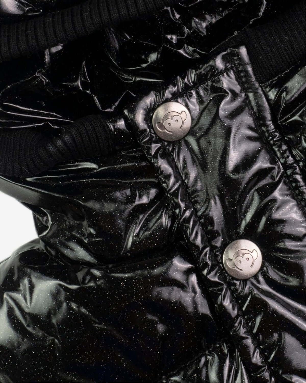 Close-up of sparkly black glitter puffy coat buttons and cozy fabric, perfect for stylish kids' winter adventures!