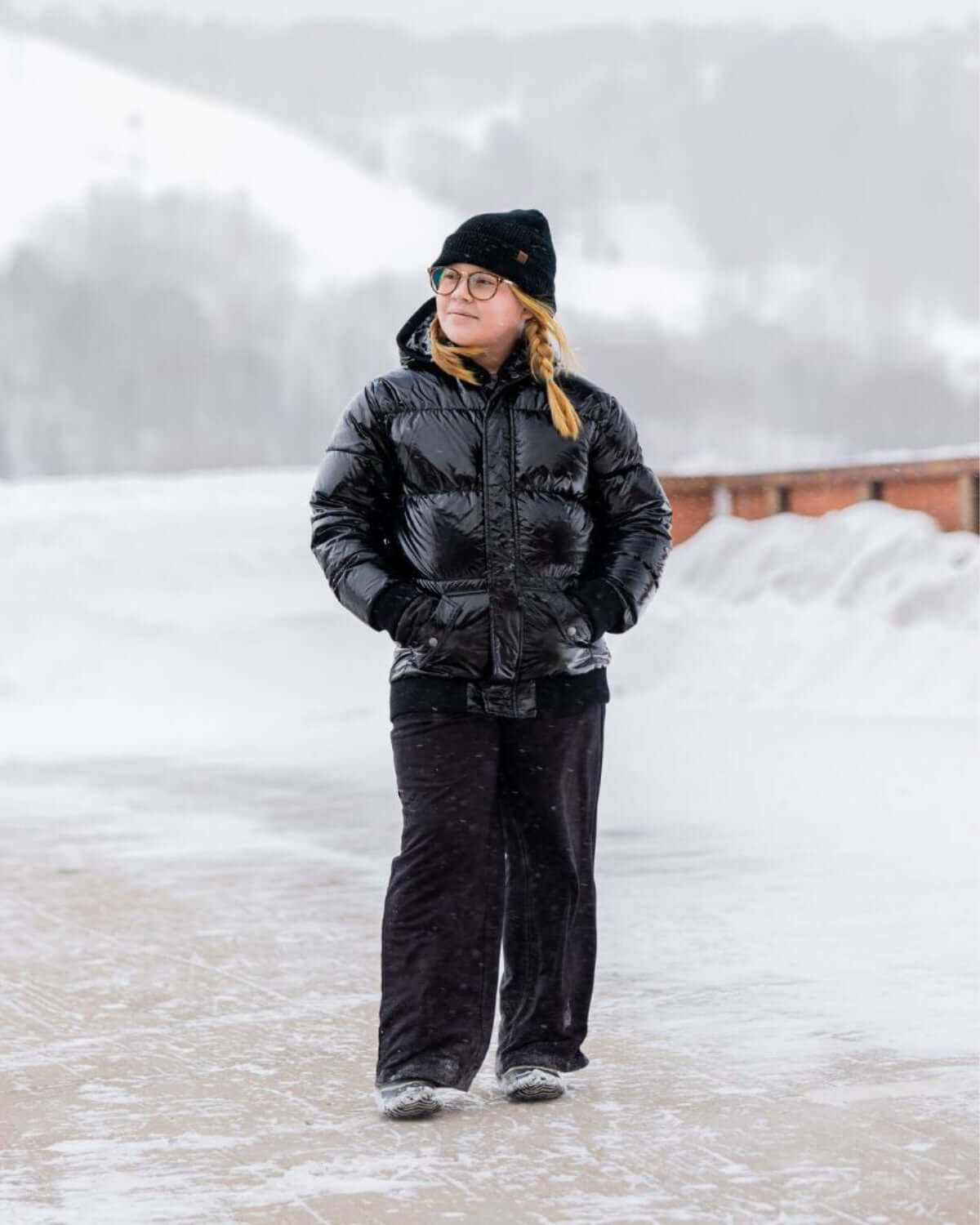 Chic kid bundled up in a shiny black puffy coat, ready for snowy adventures with style and warmth!