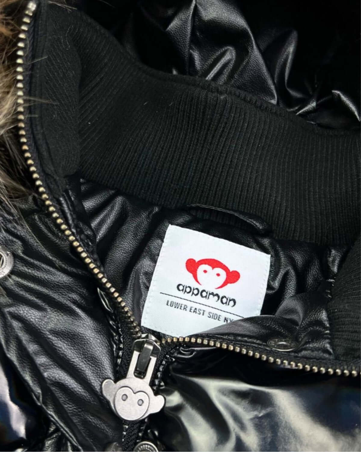 Inside view of the stylish Appaman Kyla Puffer Coat, featuring a cozy lining and playful monkey logo—perfect for trendy kids!