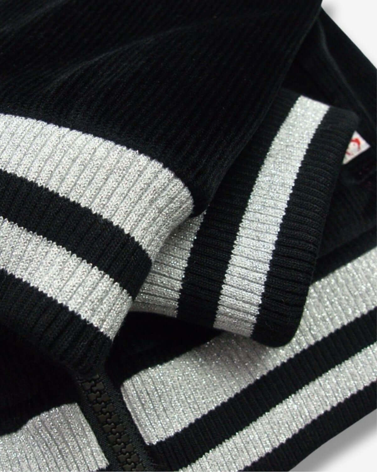 Close-up of stylish black velvet bomber jacket's sparkly ribbing, perfect for kids' back to school fashion.