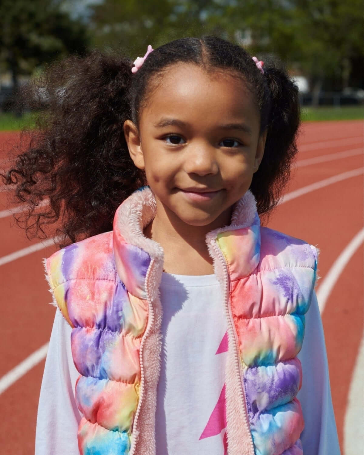A smiling girl wearing the colorful Candy Cloud Reversible Vest, ready for fun adventures in stylish kids clothes.