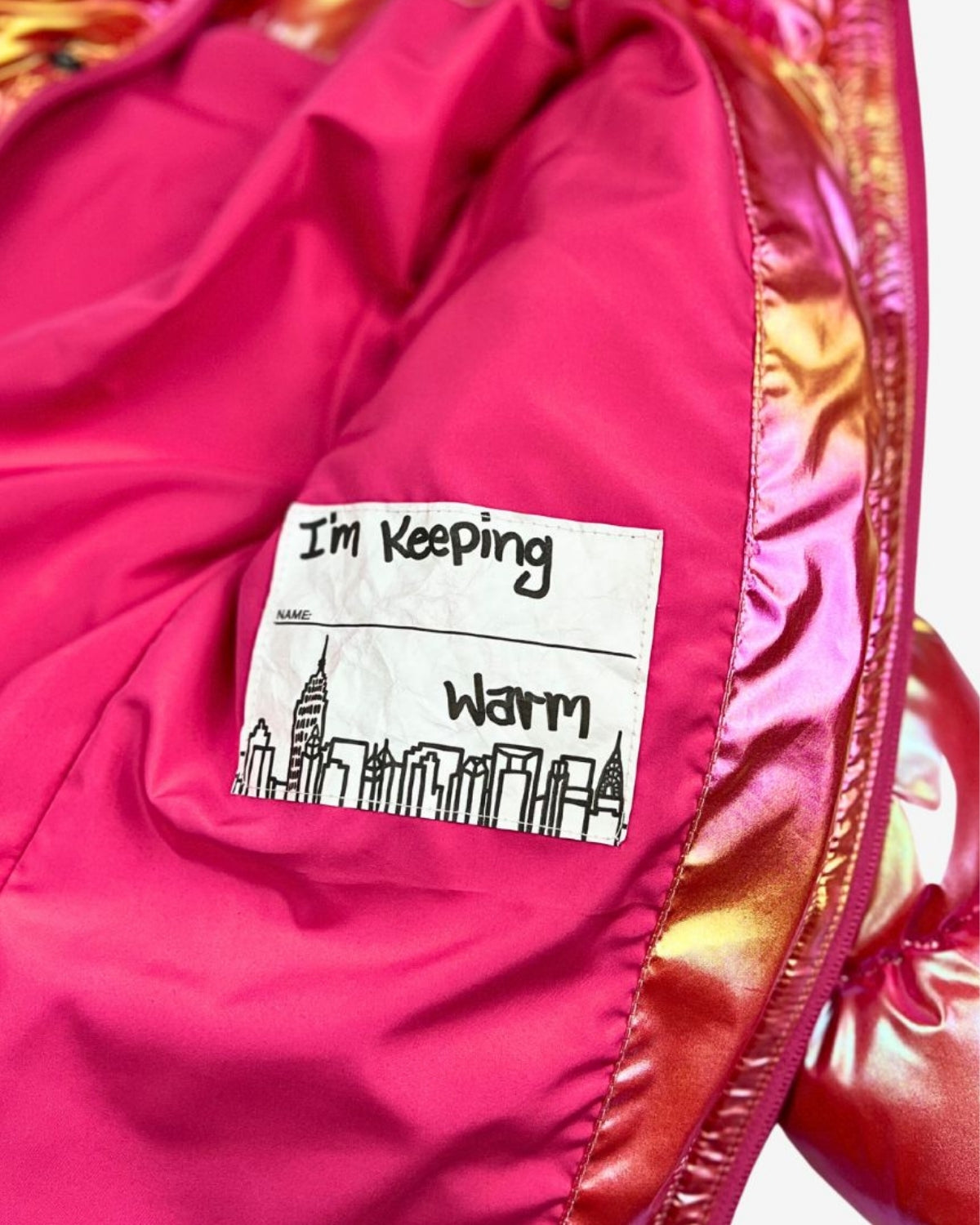 Inside label on a vibrant pink puffy coat saying "I'm Keeping Warm"—a fun reminder of cozy style for kids.