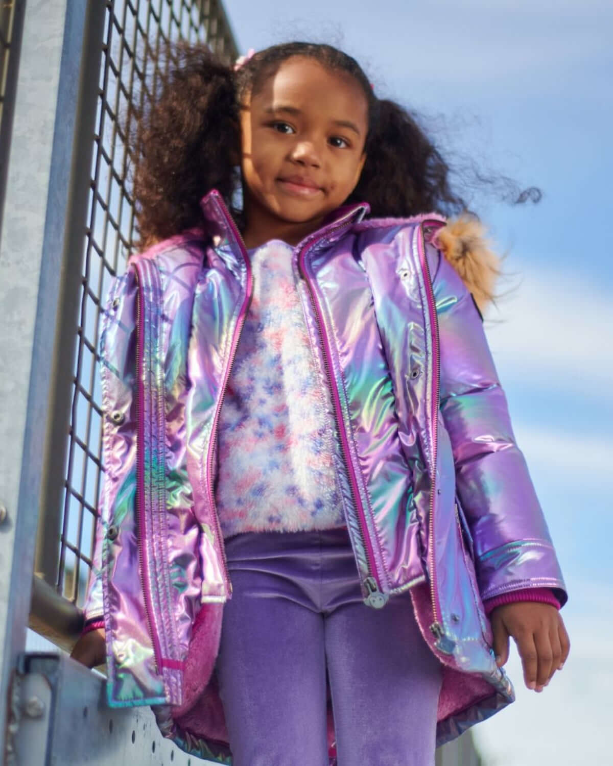 Stylish girl in a vibrant, iridescent puffer coat, ready for winter adventures in chic comfort and warmth.