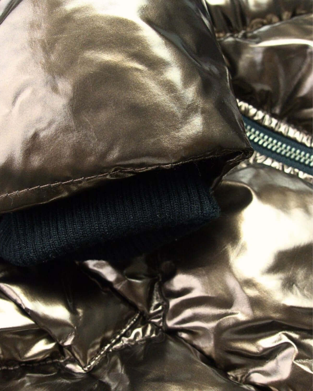 Close-up of the shiny Copper Nova Long Coat showcasing cozy cuff and stylish zipper, perfect for chic winter warmth.