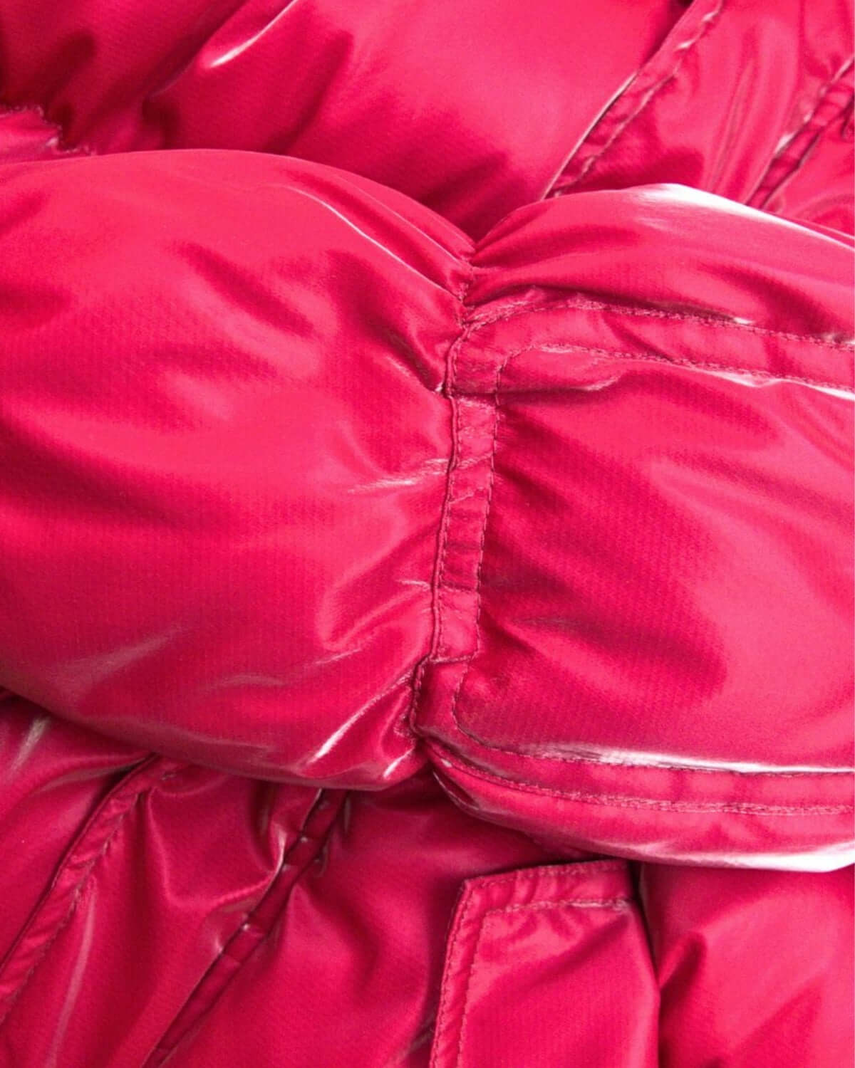 Close-up of deep pink puffy coat, showcasing its cozy, stylish fabric designed for playful winter adventures.