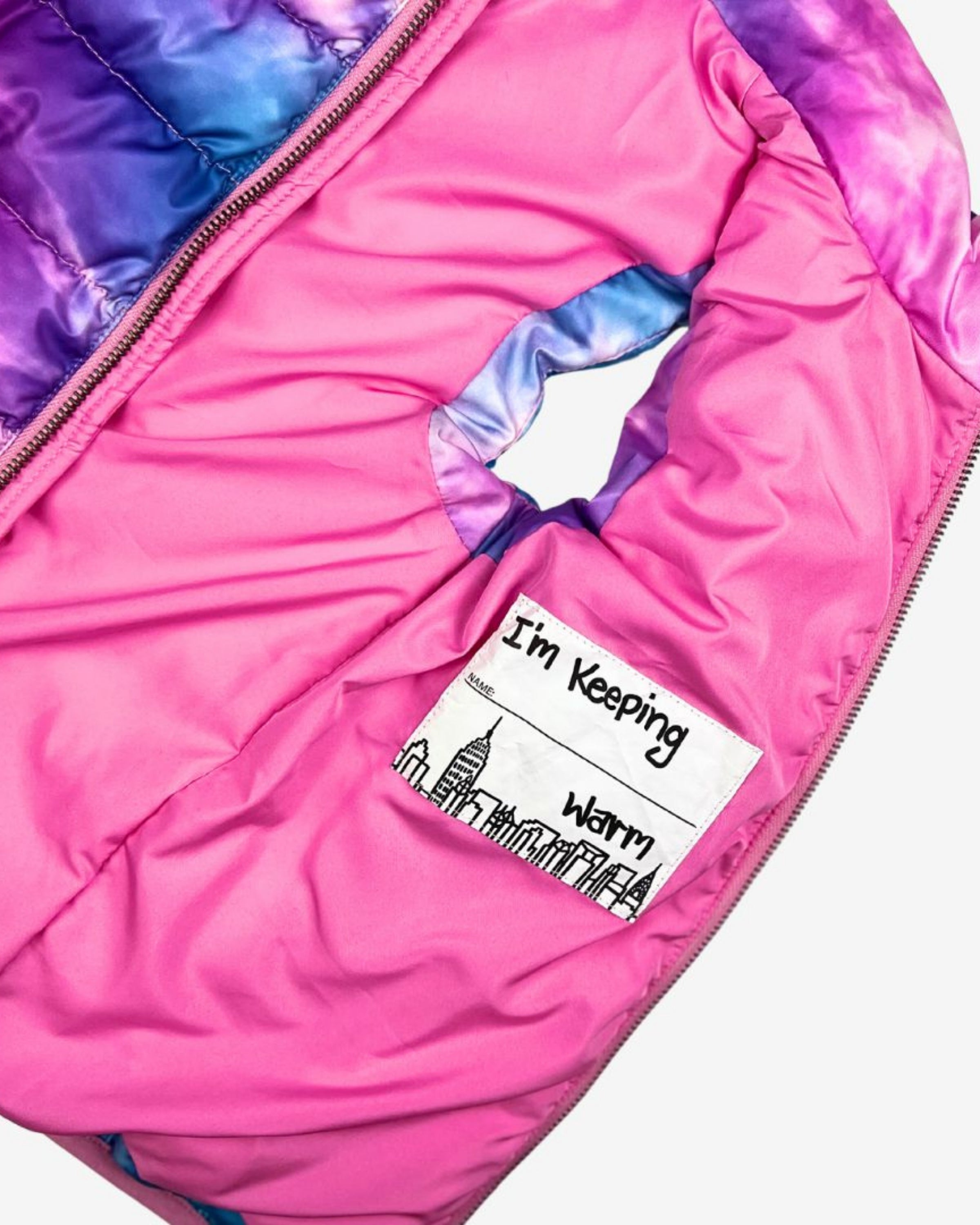 Inside view of the Dream Cloud Reversible Puffer Vest featuring a playful pocket with 'I'm Keeping Warm' design.