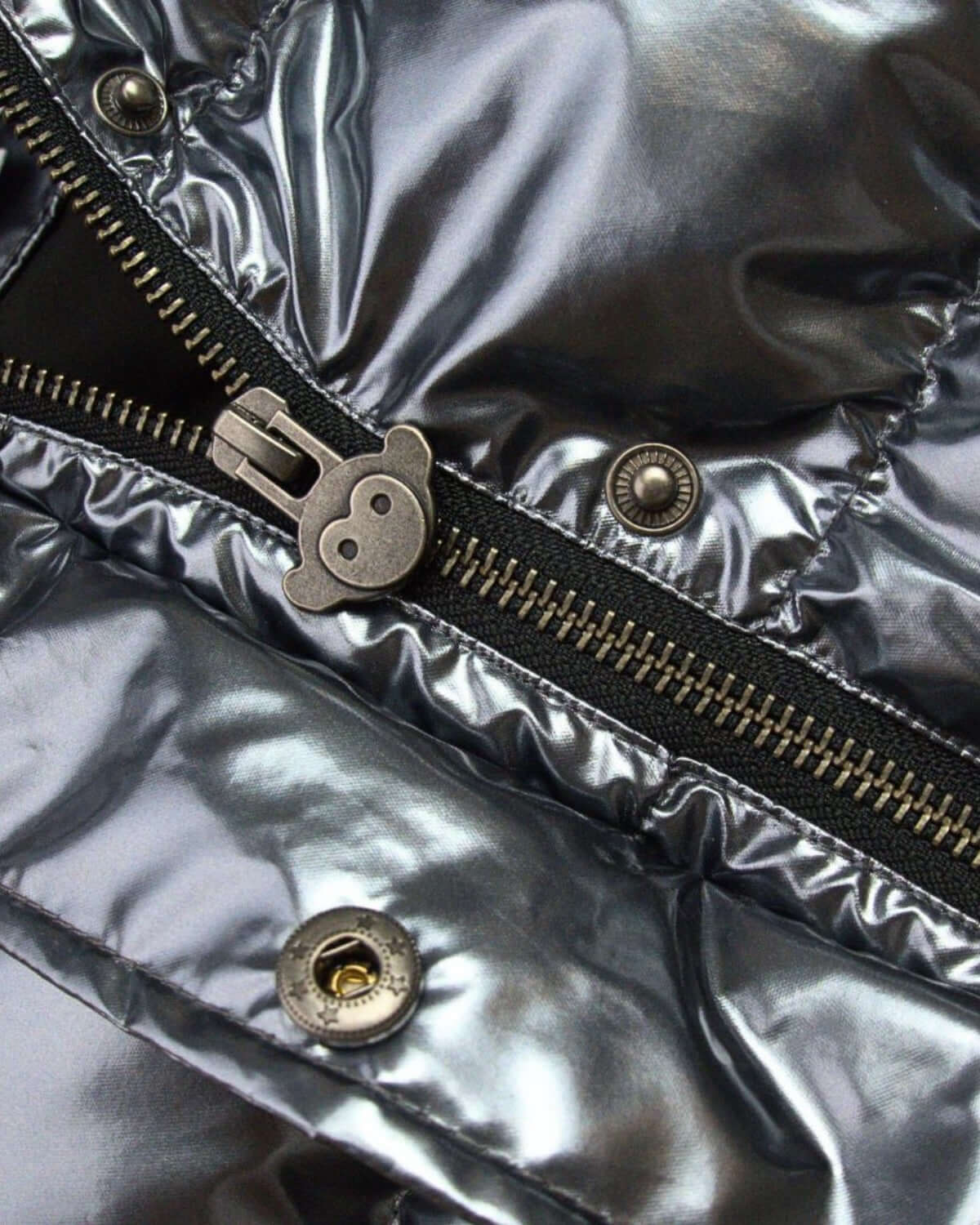 Close-up of the shiny gunmetal zipper and snap buttons on the stylish Kyla Puffer Coat for kids.