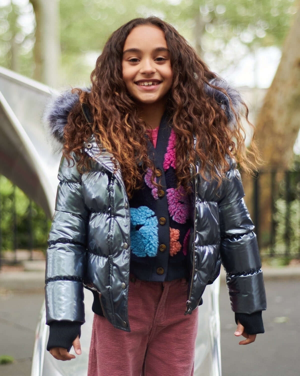 Stylish girl smiling in a shiny gunmetal Kyla Puffer Coat with faux fur hood, perfect for fun winter days!
