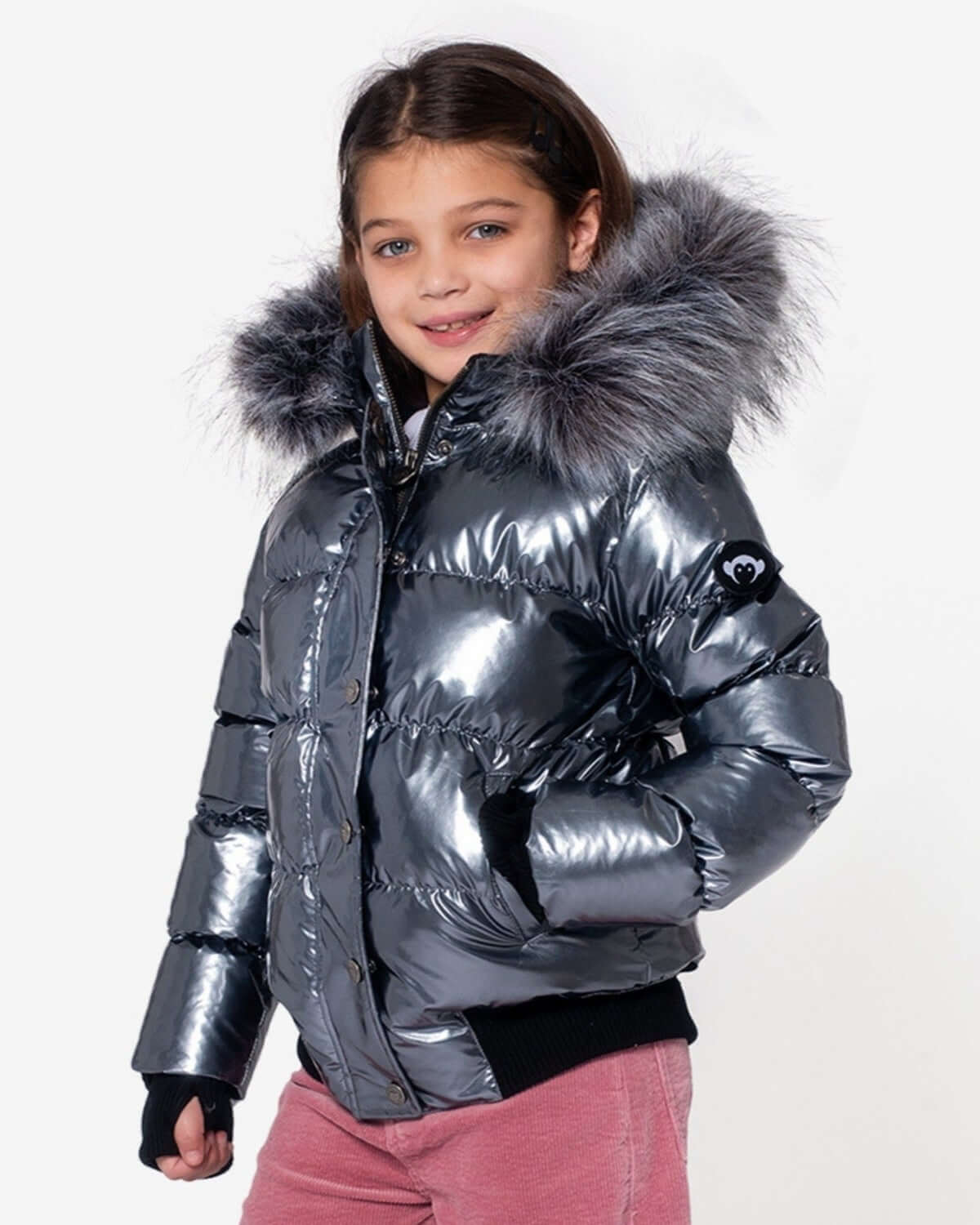 Stylish girl in a shiny gunmetal puffer coat with faux fur hood, making winter fun and fashionable!