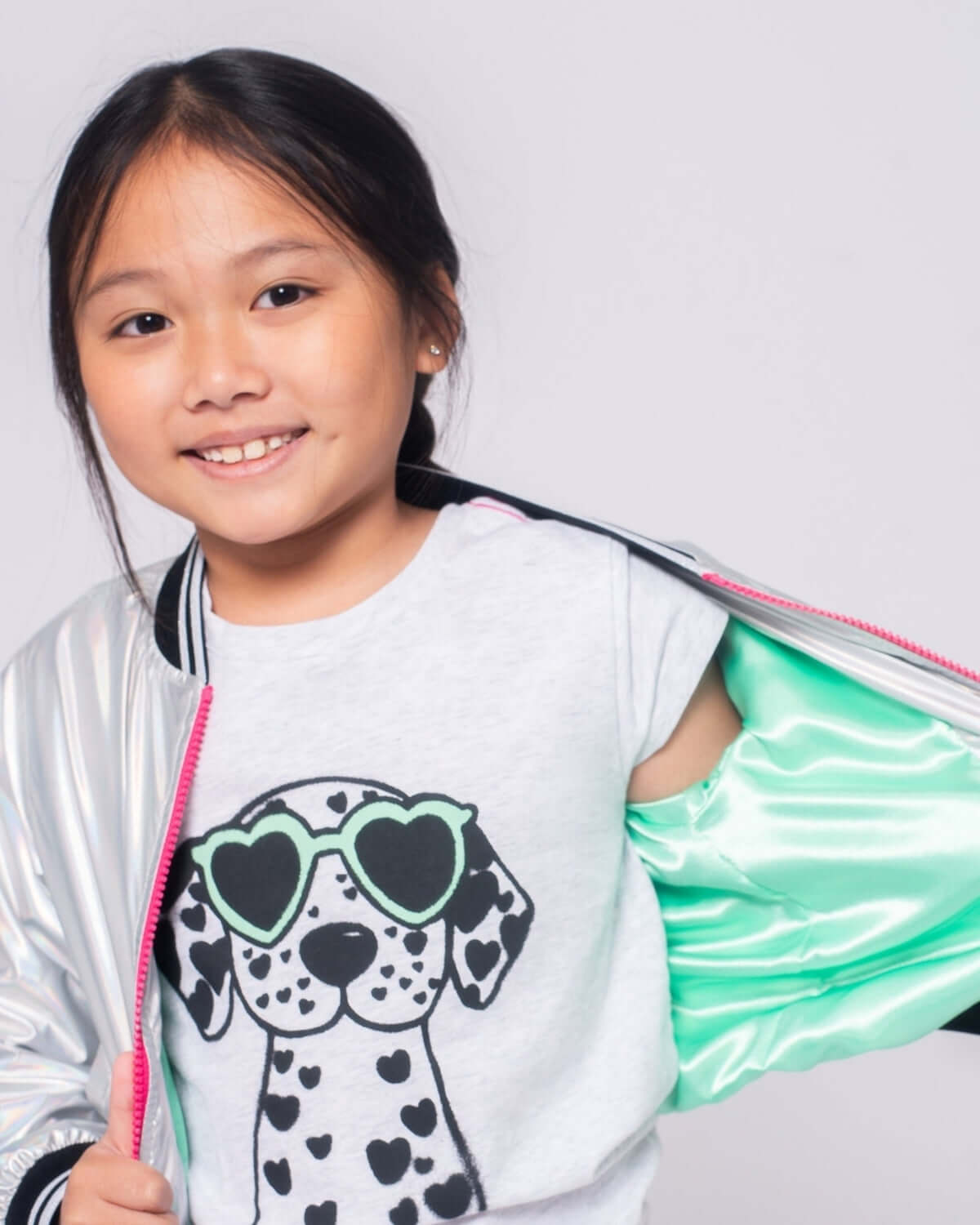 Girl wearing an Iridescent Nikki Bomber Jacket over a cute dog graphic t-shirt, smiling confidently.