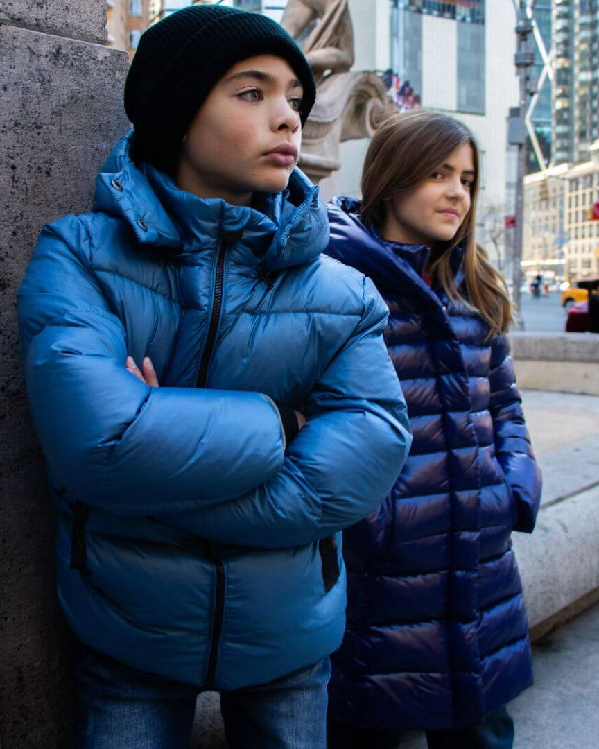 Stylish kids rocking cozy blue puffer jackets in the city, blending warmth and fun for back to school adventures.