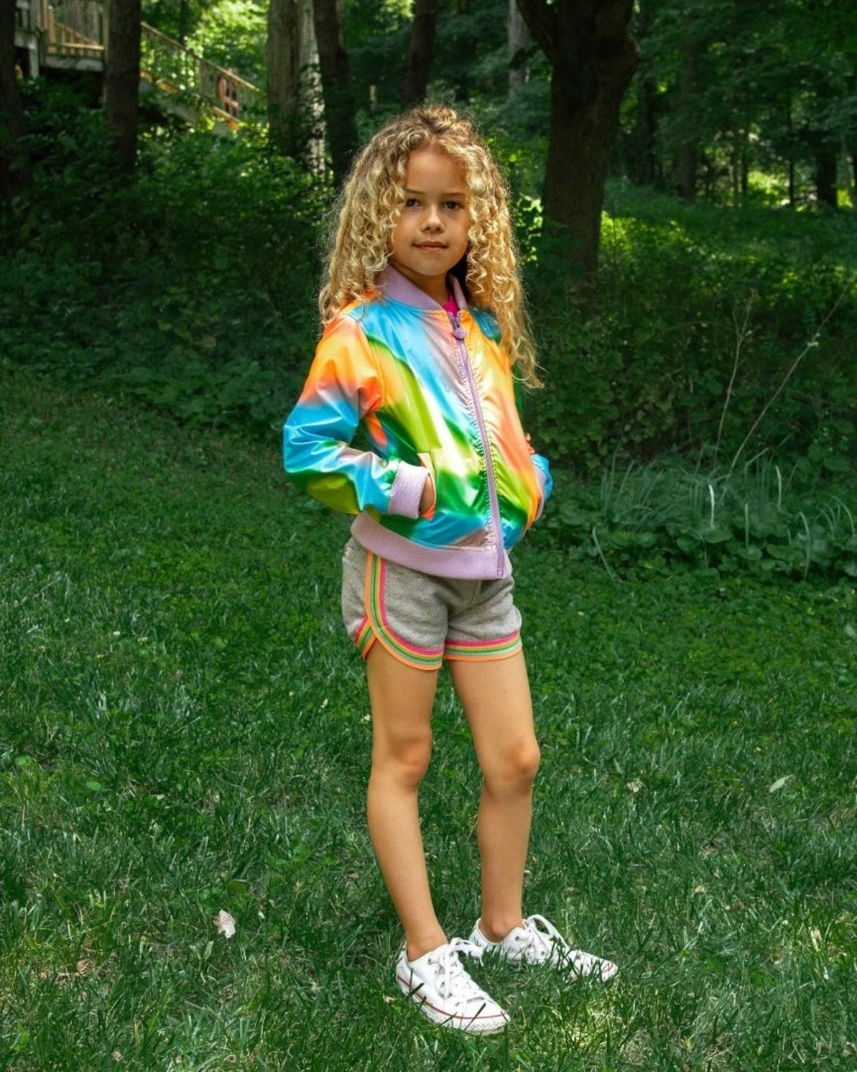 Stylish girl in a vibrant rainbow bomber jacket, perfect for kids clothes that shine bright in any back to school adventure!