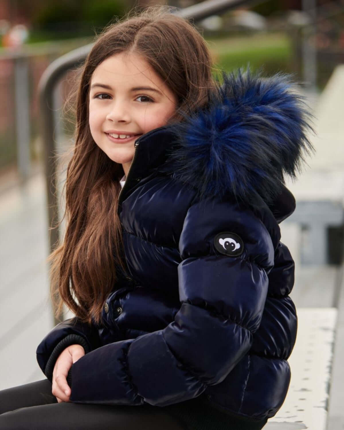 Stylish girl in a navy puffer coat with faux fur hood, perfect for keeping warm in winter adventures!