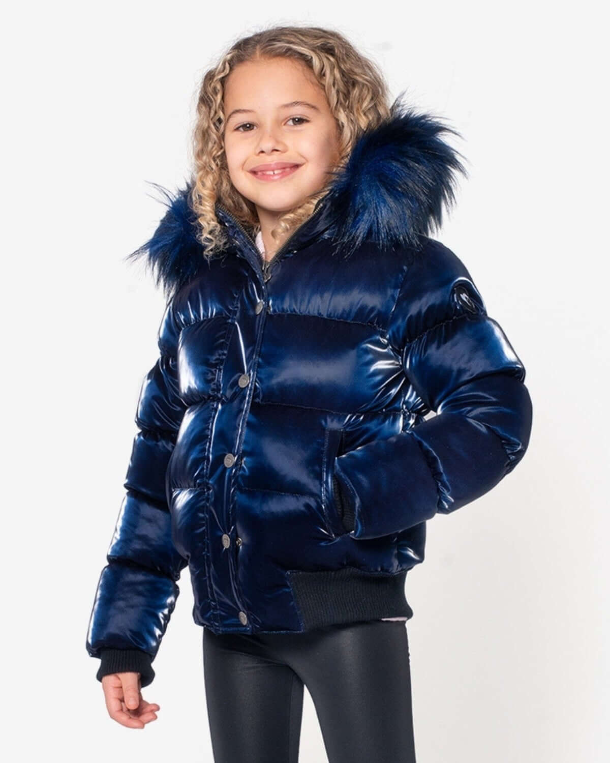 Stylish girl in a navy shine puffer coat with faux fur hood, ready for winter adventures in high-quality kids clothes.