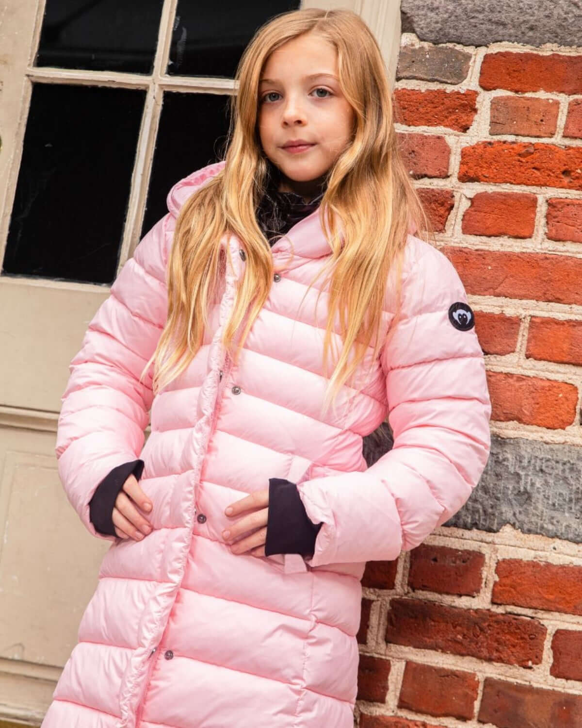 Stylish girl in a pink Lovi Long Puffer, embracing warmth and playfulness for back to school adventures.