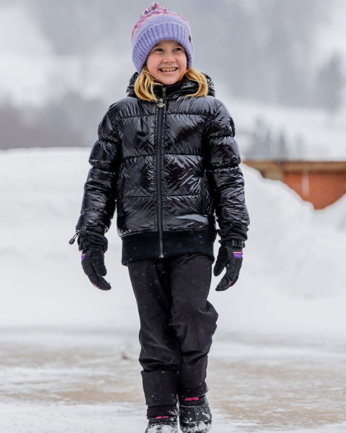 Happy girl in shiny black flurry coat and cozy hat, ready for winter fun! High-quality kids clothes for winter adventures.