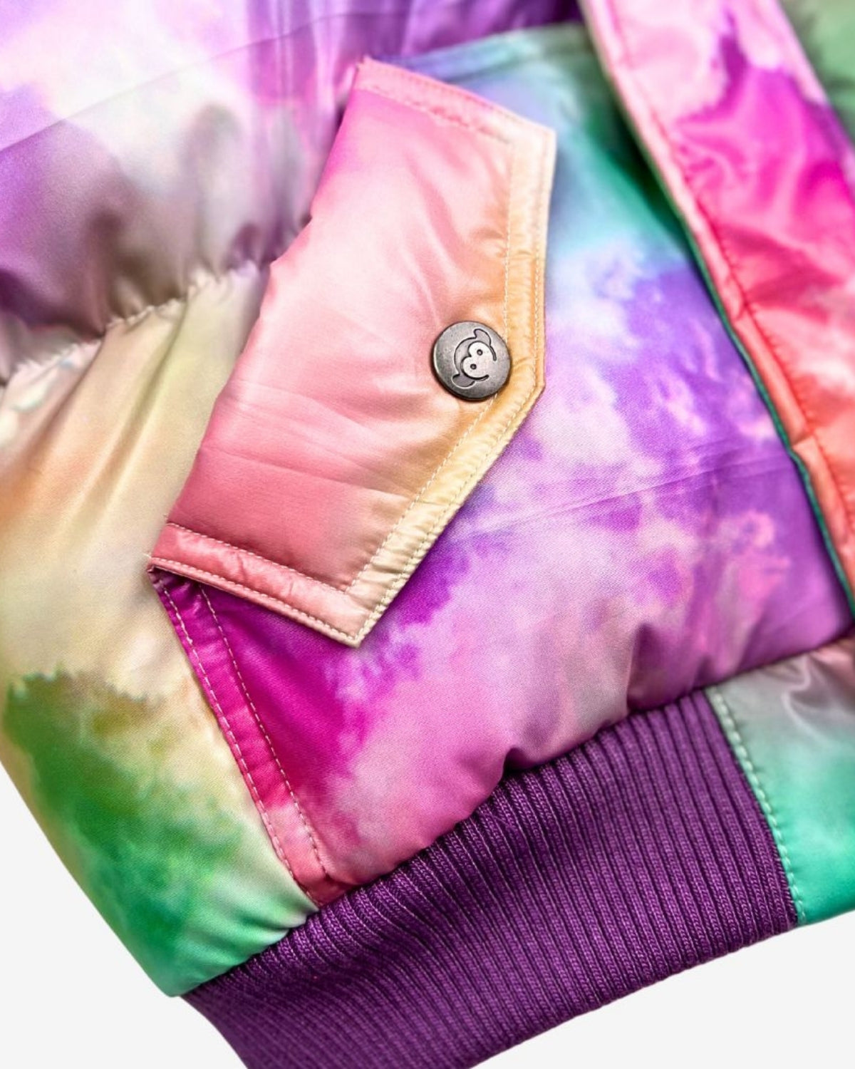 Close-up of the vibrant Watercolor Puffy Coat showcasing colorful tie-dye fabric and stylish pocket detail for kids' fashion.