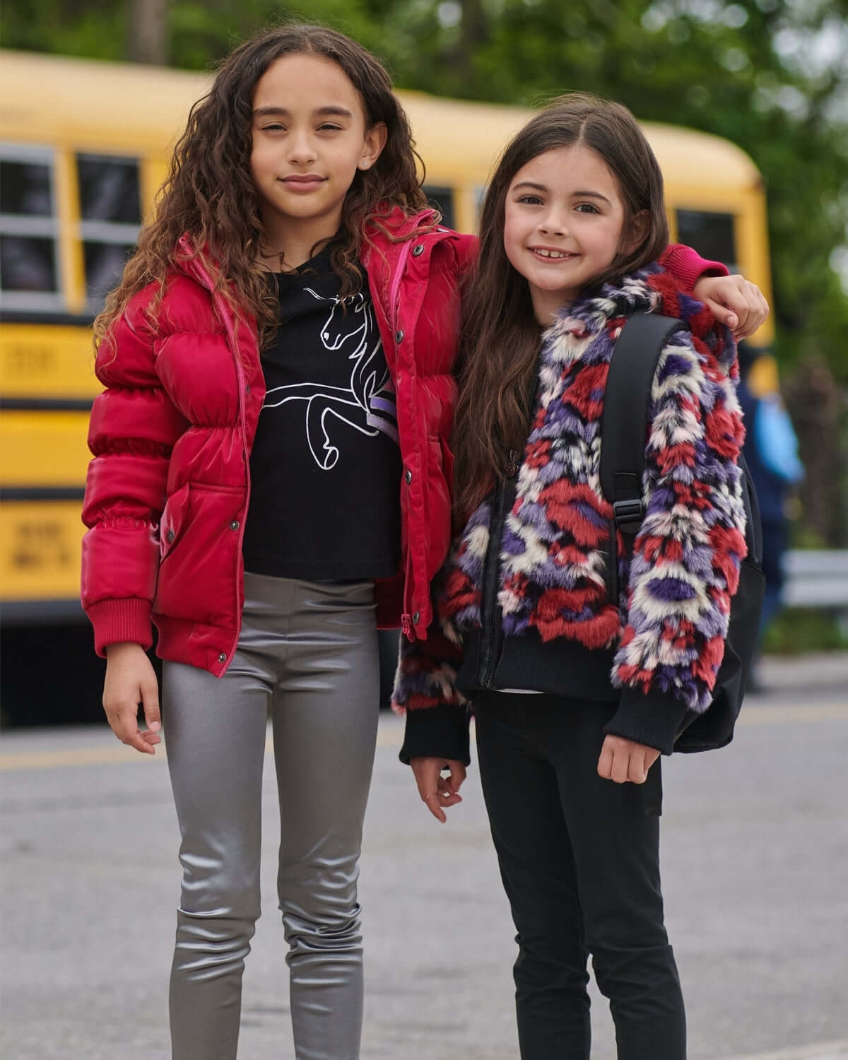 Two stylish girls in vibrant winter jackets, showcasing playful kids clothes for bold back-to-school adventures.