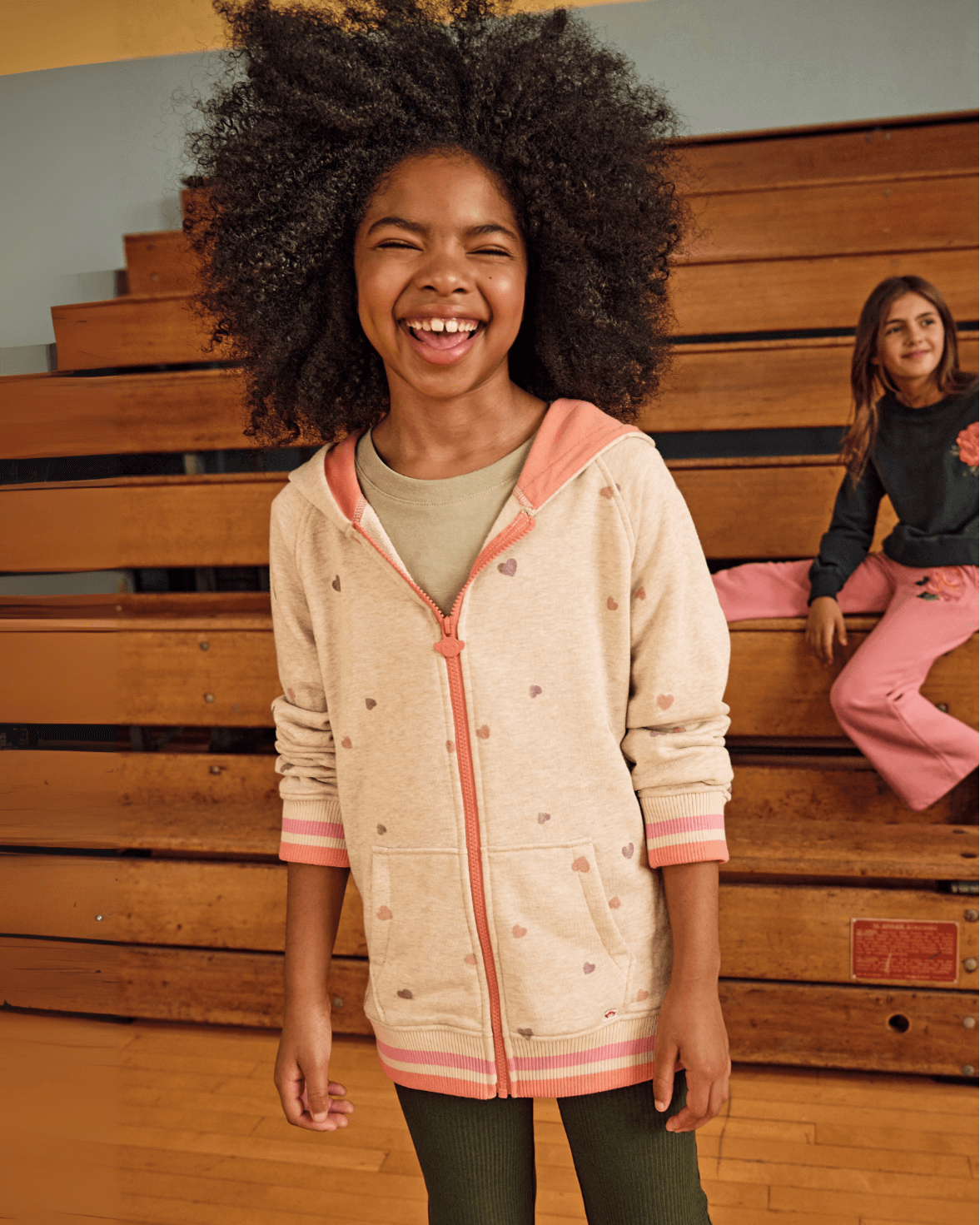 Heart Sweat Set hoodie worn by a girl in a gymnasium, smiling and showcasing its fun design and cozy fit.