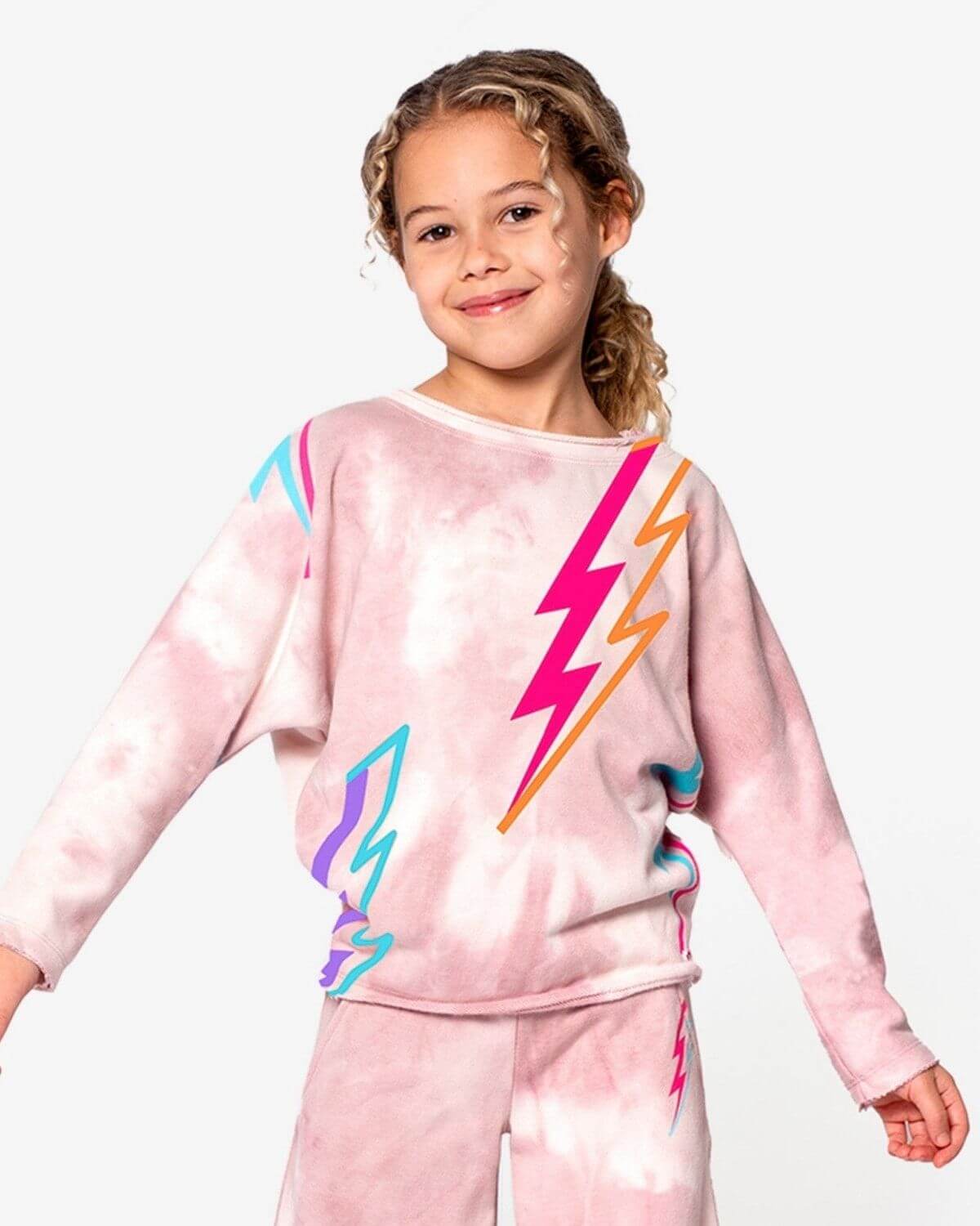 Stylish girl in a pale pink tie-dye sweatshirt with vibrant lightning bolts, perfect for kids' back to school fashion.