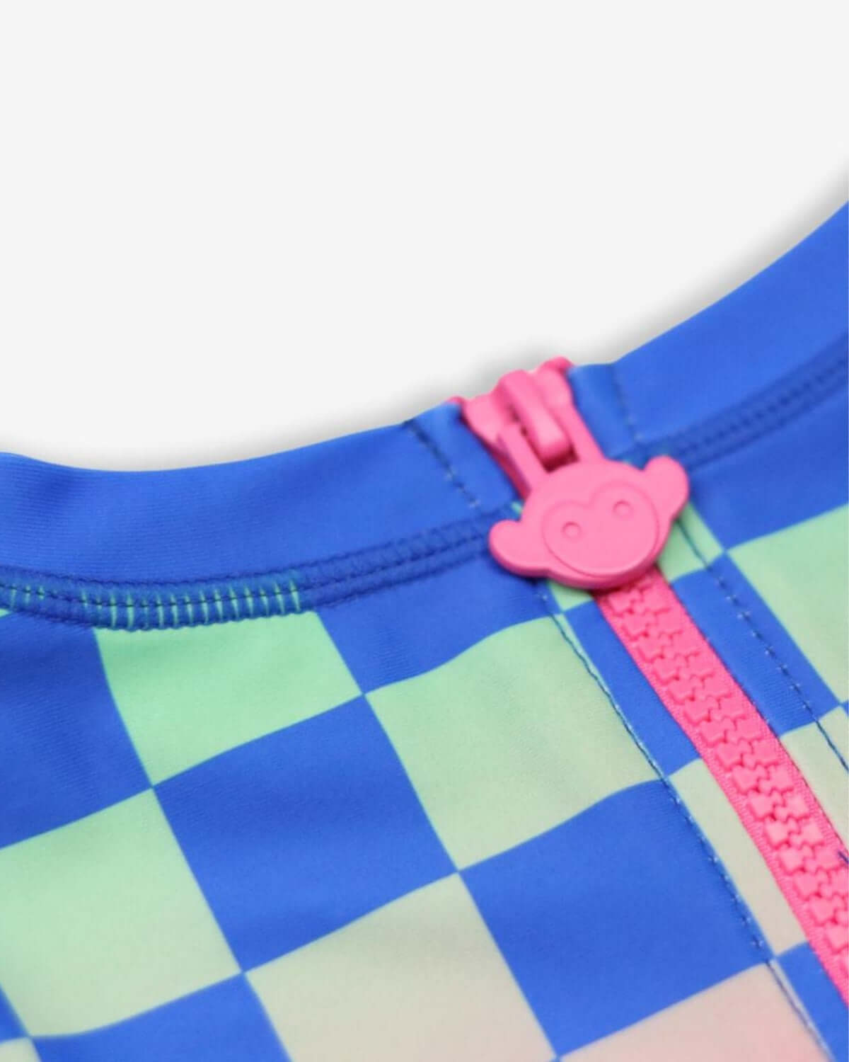 Close-up of vibrant checkerboard rash guard zipper, featuring playful monkey pull for a fun touch in kids' beachwear.