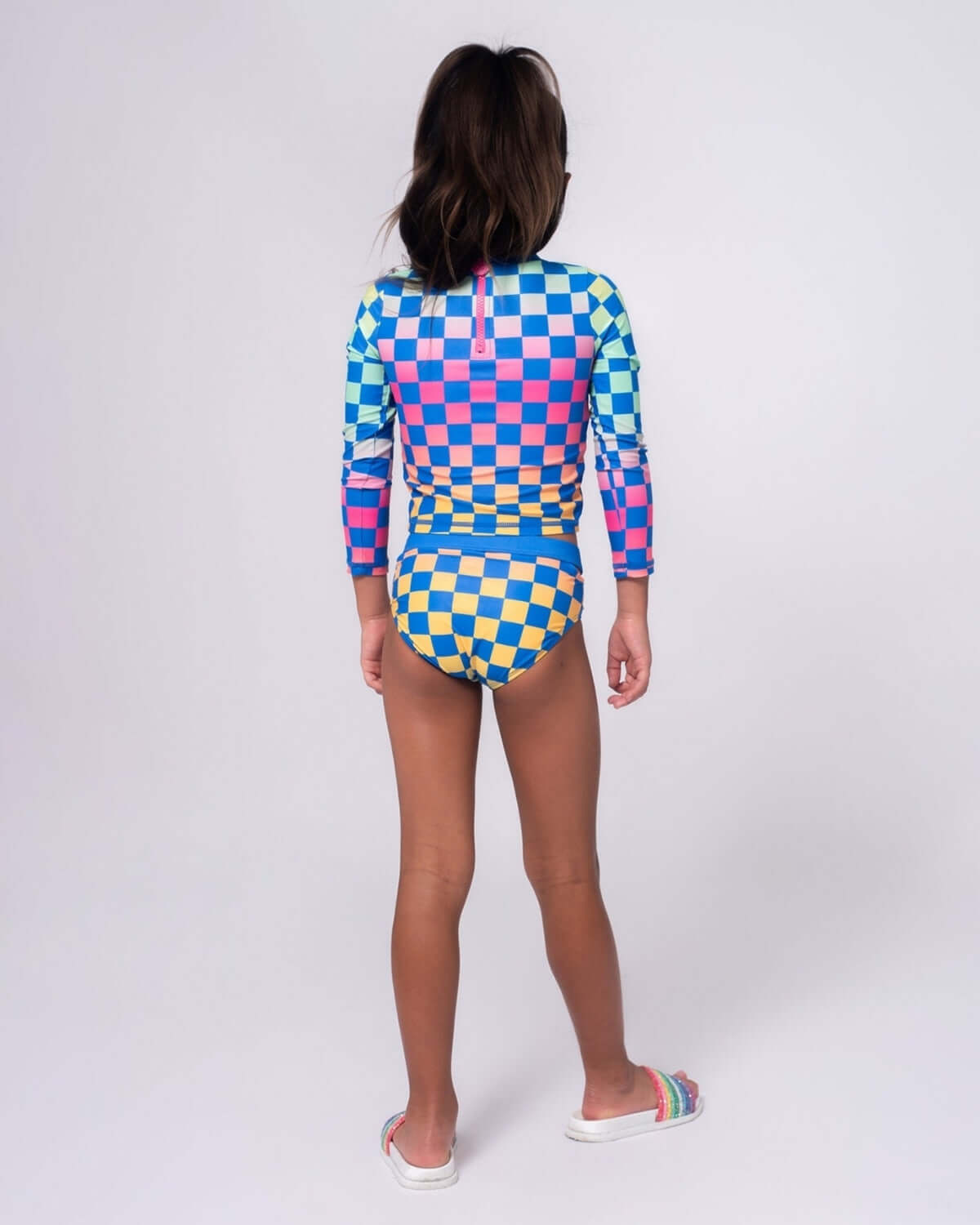 Checkerboard Oceana Rash Guard Set worn by a girl, showcasing a vibrant checkerboard print in blue, pink, and yellow.
