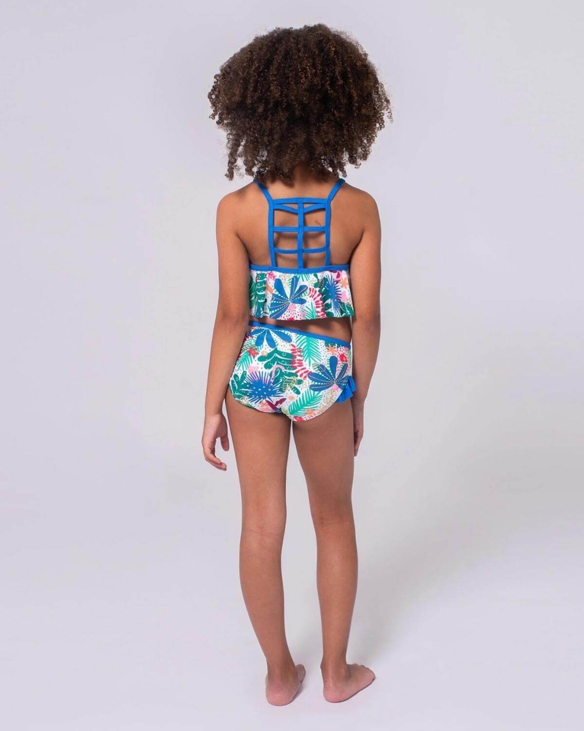 Stylish girl in a colorful floral bikini set, ready for beach fun with playful ruffles and vibrant blue accents.