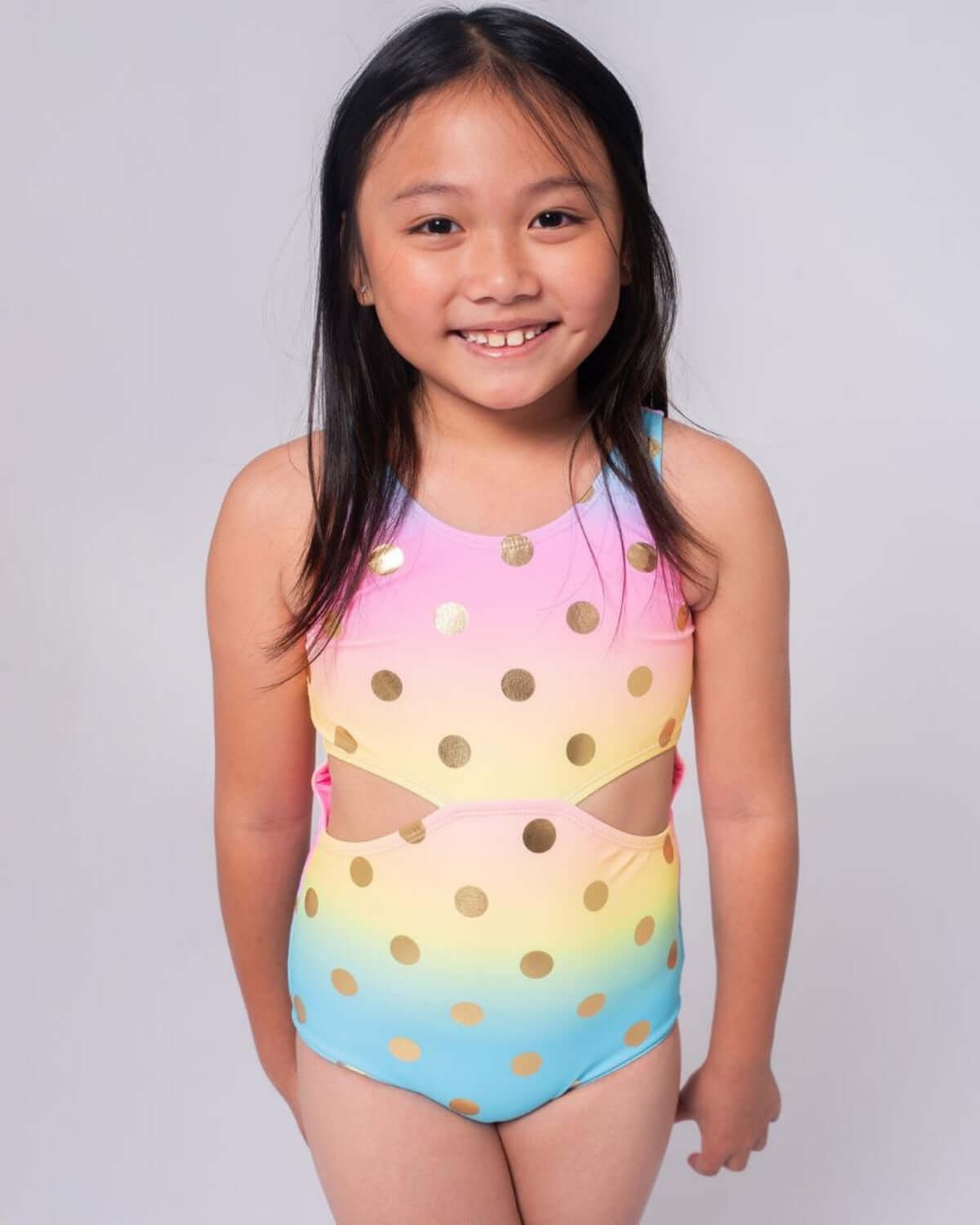 Girl wearing Rainbow Dots Erika Swimsuit with colorful polka dots and a cheerful design.