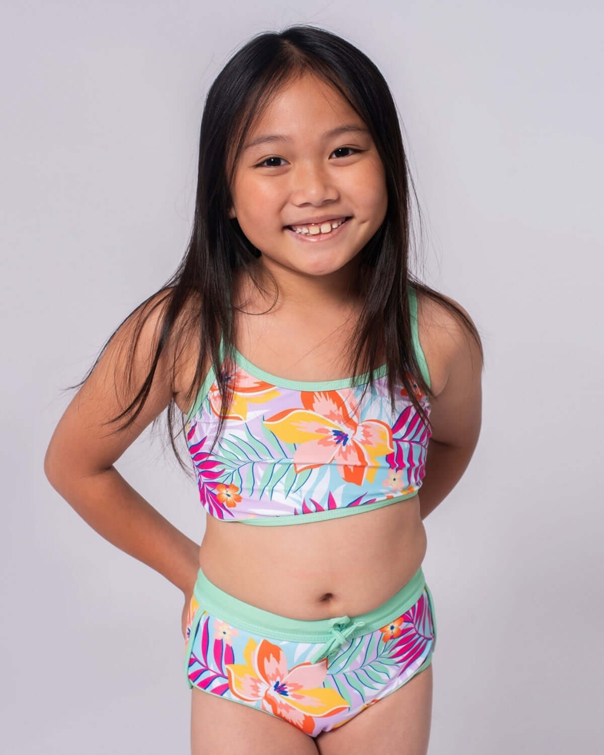 Bright and playful girl wearing Retro Tropics Stella Bikini, showcasing vibrant floral print for fun summer adventures.