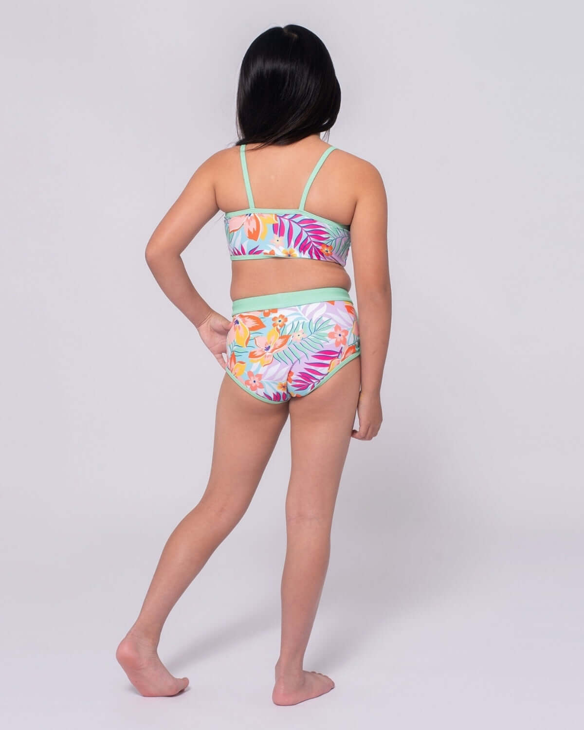 Back view of a child wearing the Retro Tropics Stella Bikini with vibrant floral design and fresh green accents.