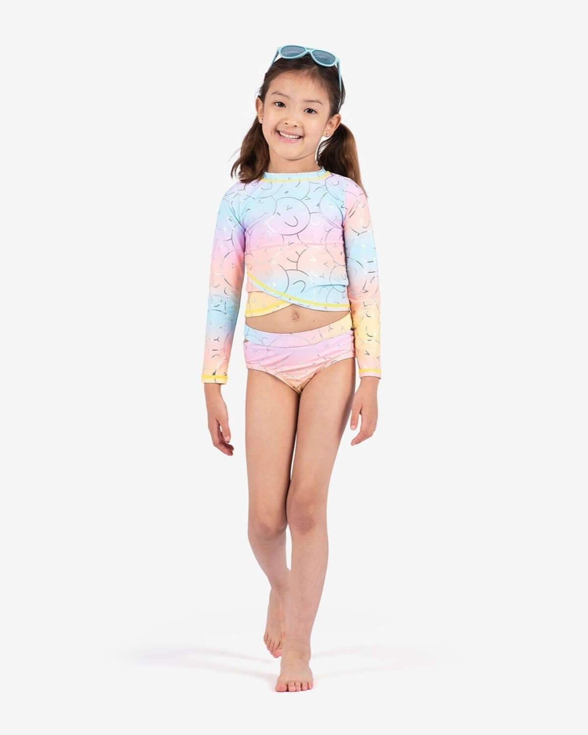 Happy child in vibrant Summer Joy Oceana bikini set, featuring fun smiley faces and colorful ombre design for stylish summer adventures.