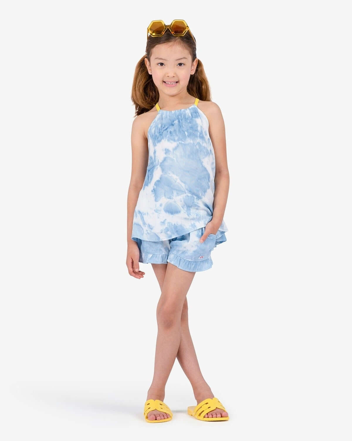 Confident kid in blue tie-dye Sanibel Tank and matching shorts, ready for beach fun! Stylish kids clothes for back to school.