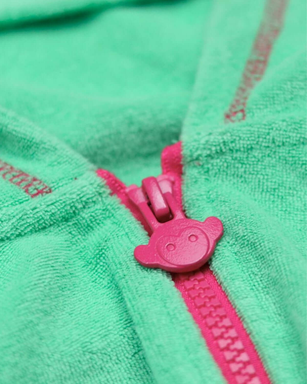 Close-up of playful pink zipper on a mint green hoodie, adding style to kids clothes for school or casual playdates.