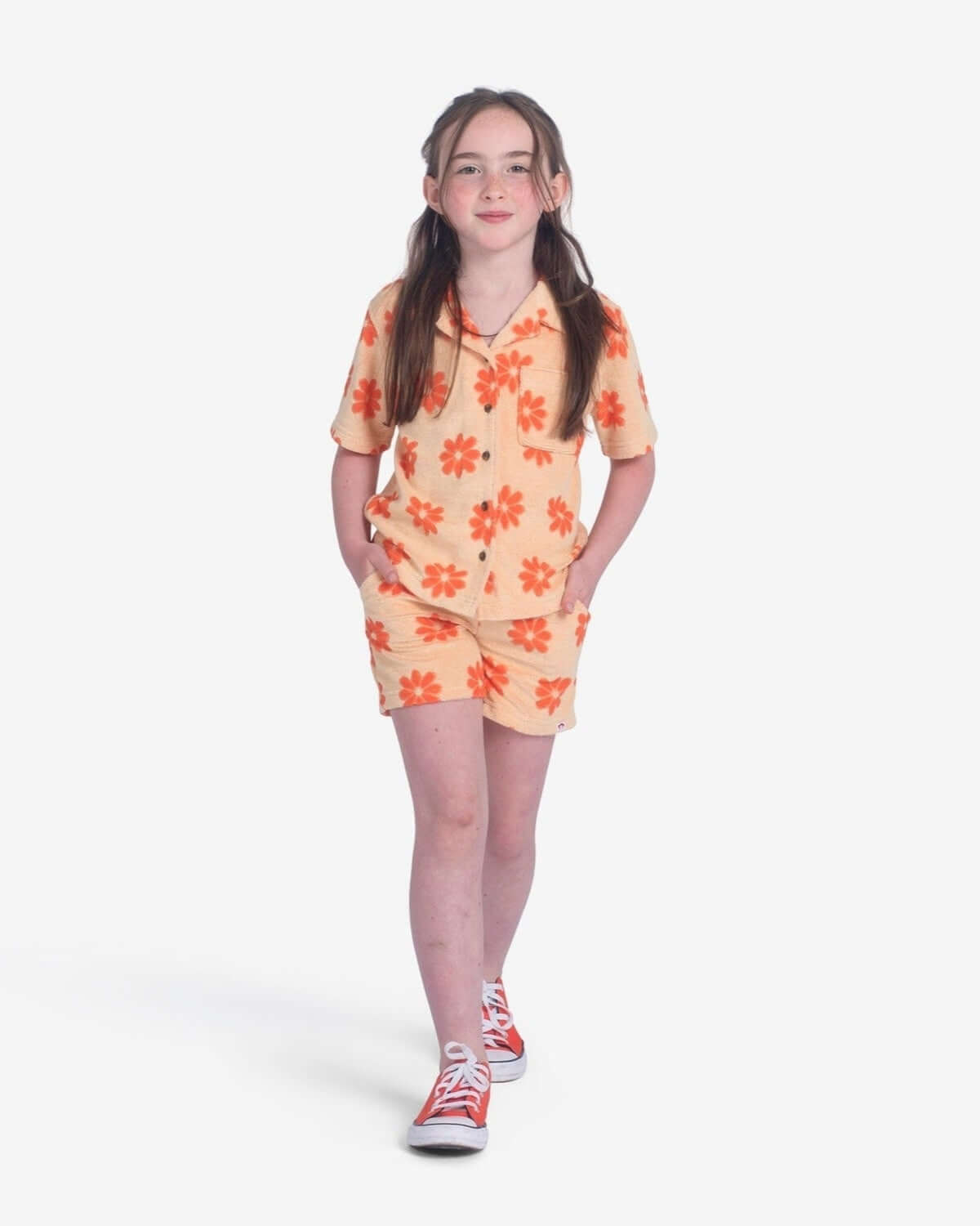 Stylish girl in light orange Daisies Resort Shirt and shorts, ready for sunny adventures in quality kids' clothes.