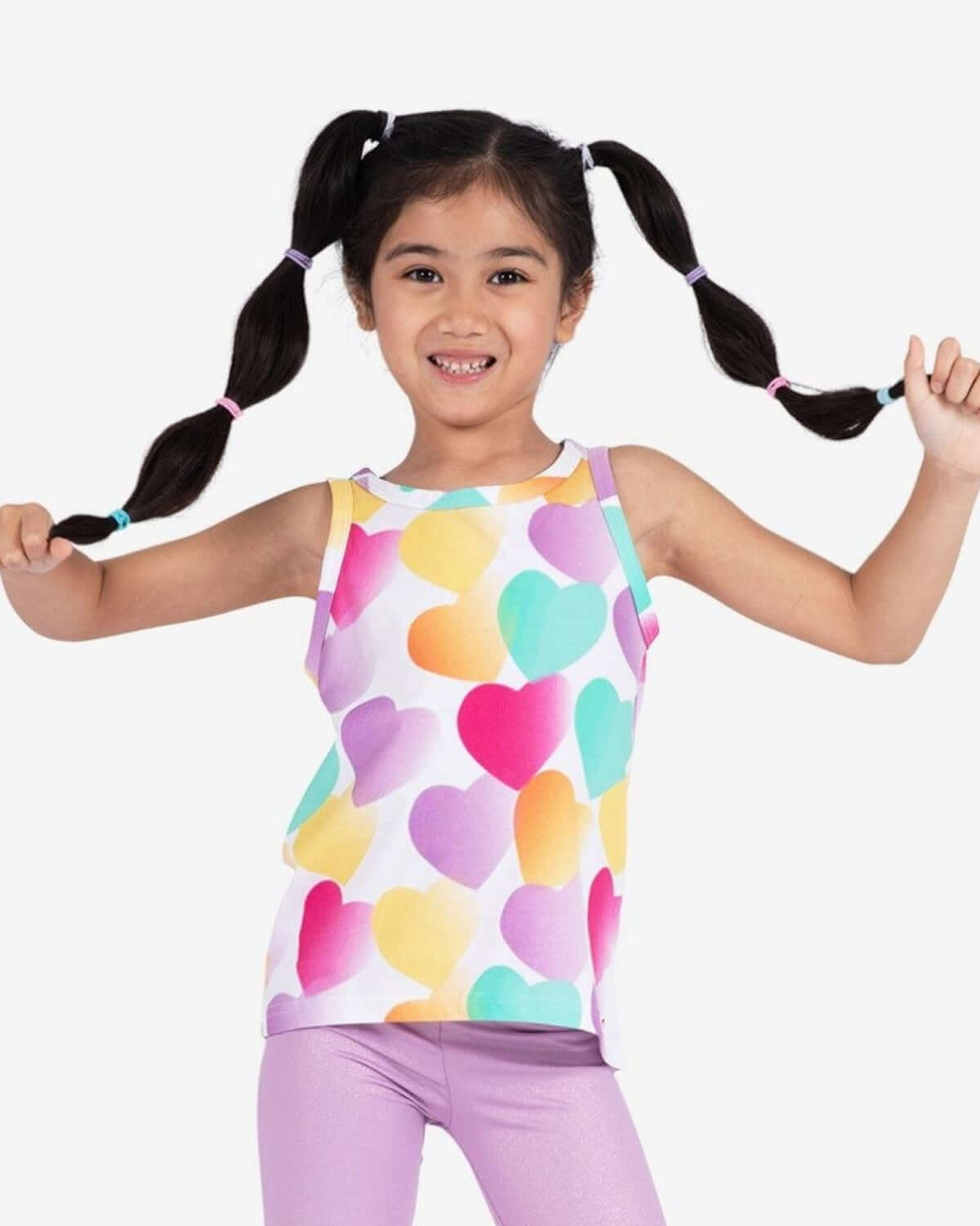 Cheerful girl in colorful heart tank top, showcasing playful style and bright spirit for kids' fashion this back to school season!