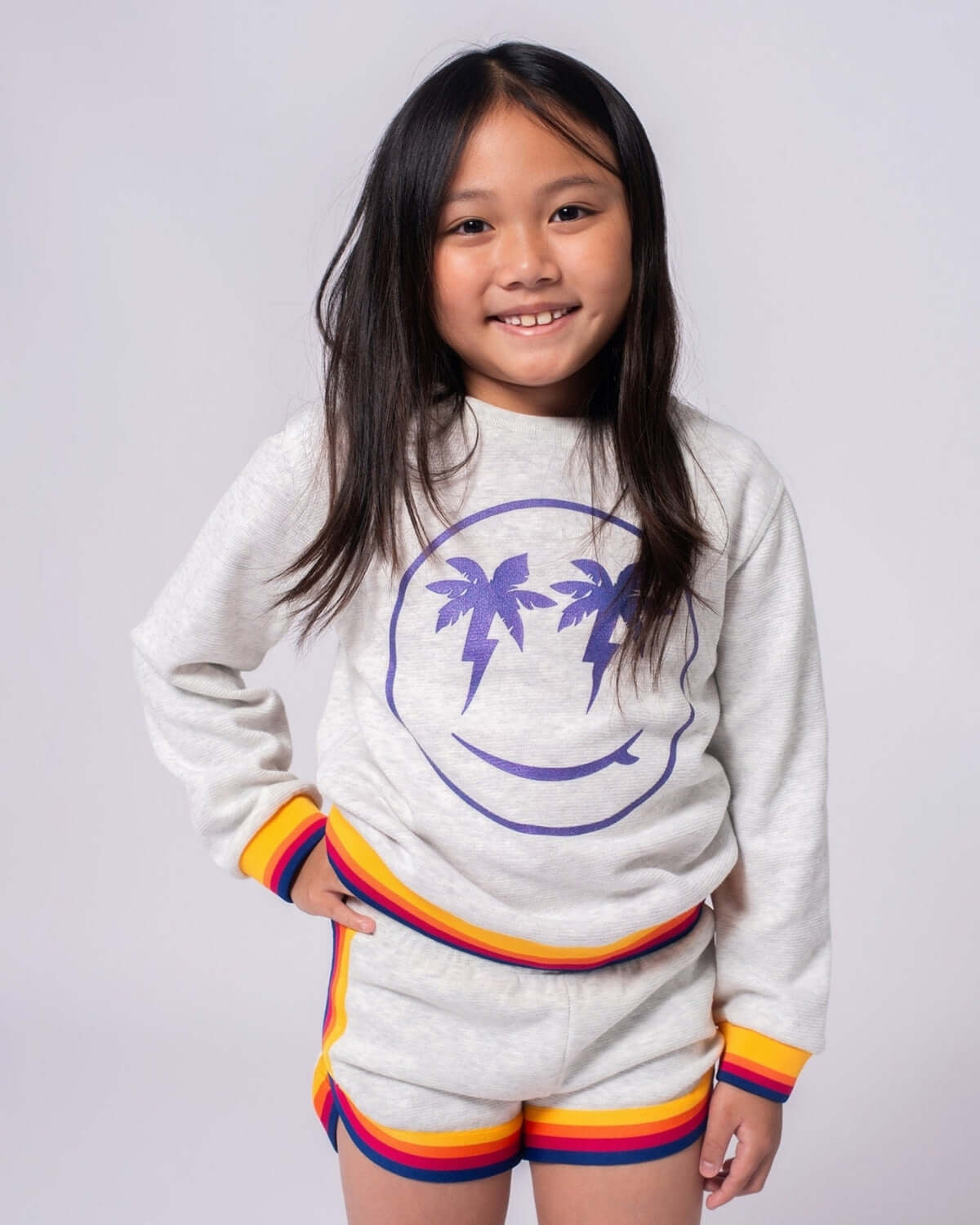 Bright-eyed kiddo rocking the Happy Surfing Ruby Sweatshirt, styled for sunny adventures in vibrant, comfy layers!