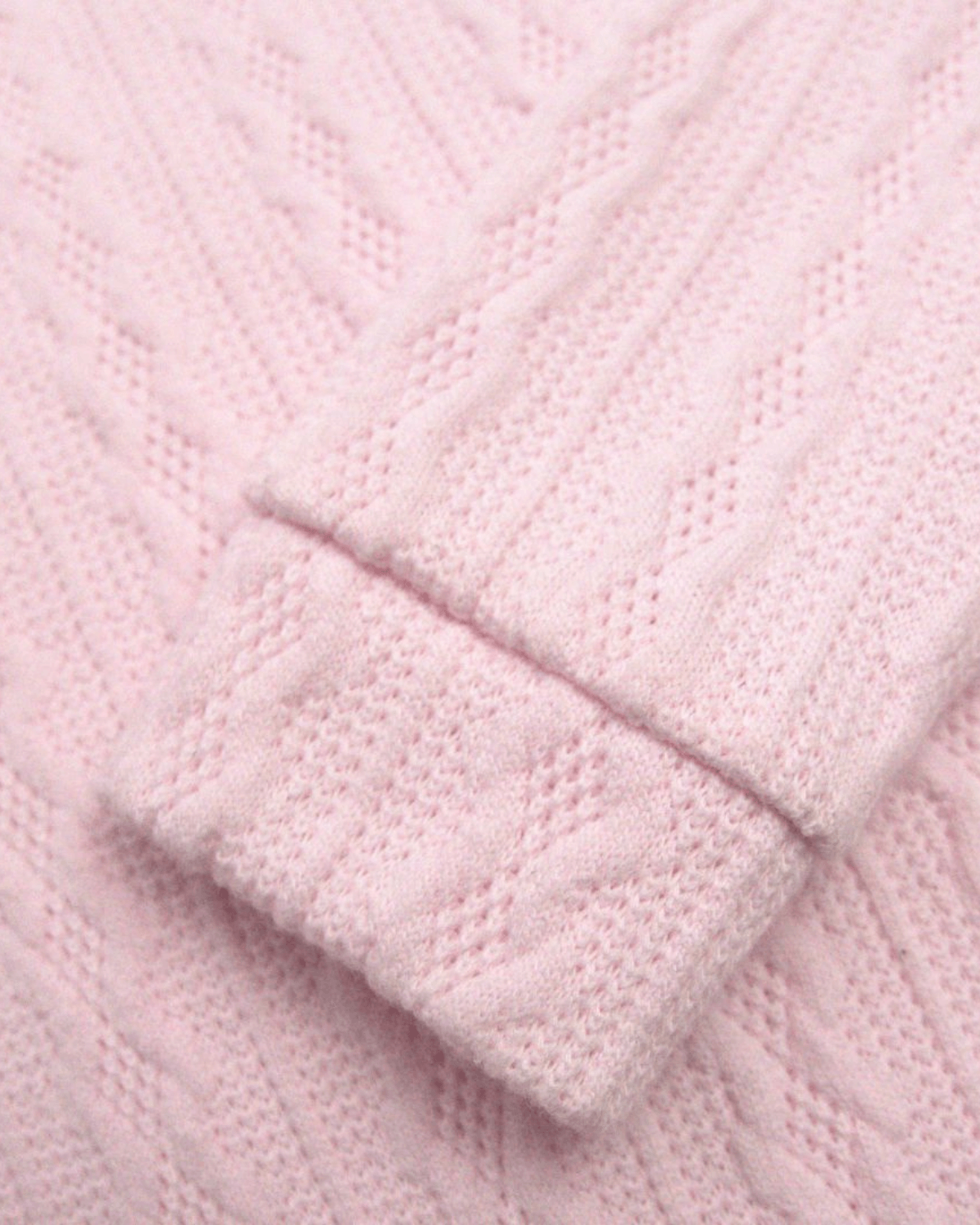 Close-up of the cozy cable knit in pale pink, perfect for kids' stylish back-to-school outfits.