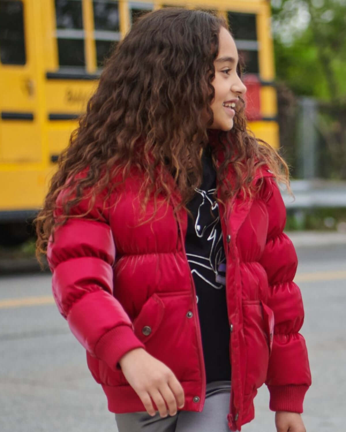 A stylish girl in a vibrant red puffer jacket, braving the schoolyard with confidence and charm.