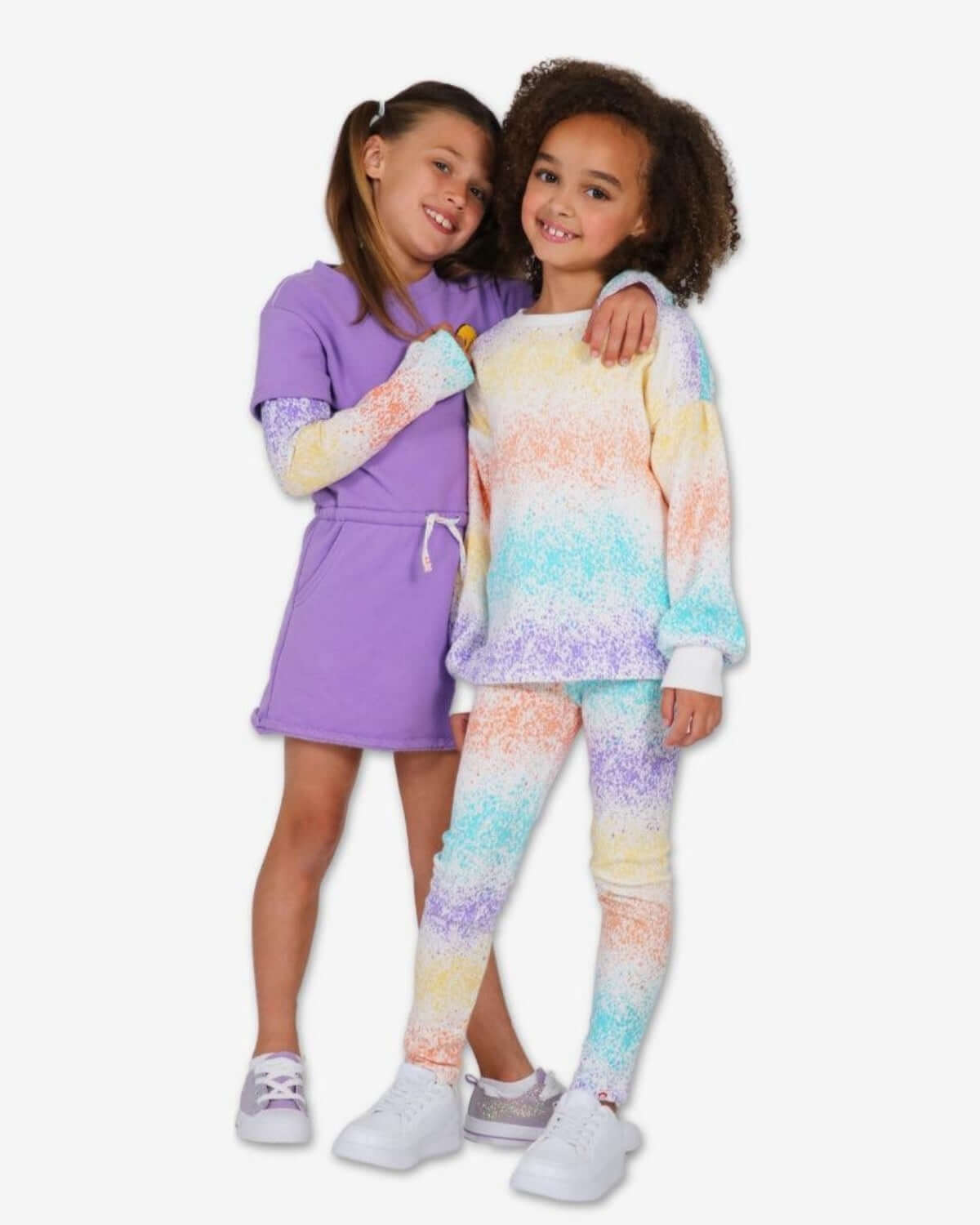 Two stylish girls in vibrant splatter print outfits, showcasing playful kids clothes for back to school fun.