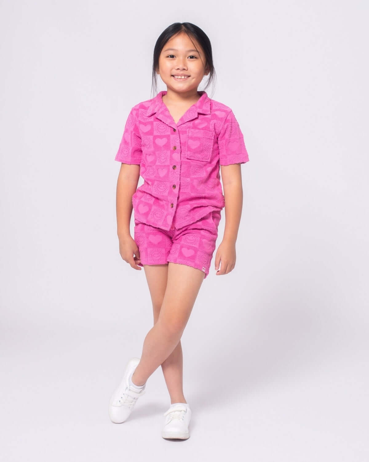 Stylish girl rocking a bright pink resort shirt and matching shorts, ready for sunny adventures in high-quality kids clothes.
