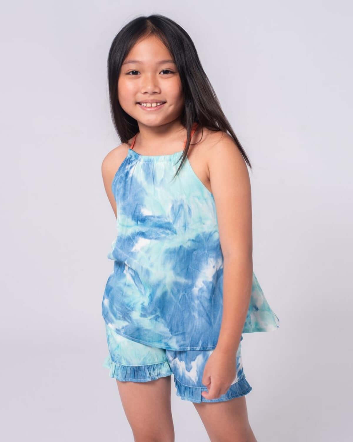 A happy girl in a vibrant turquoise watercolor tank and shorts, perfect for summer fun and back-to-school style.
